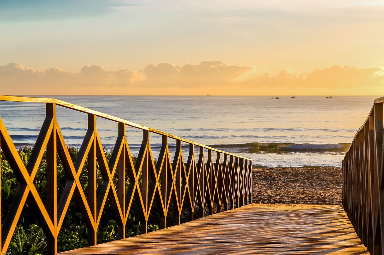 Passarela de madeira sobre a praia ao entardecer